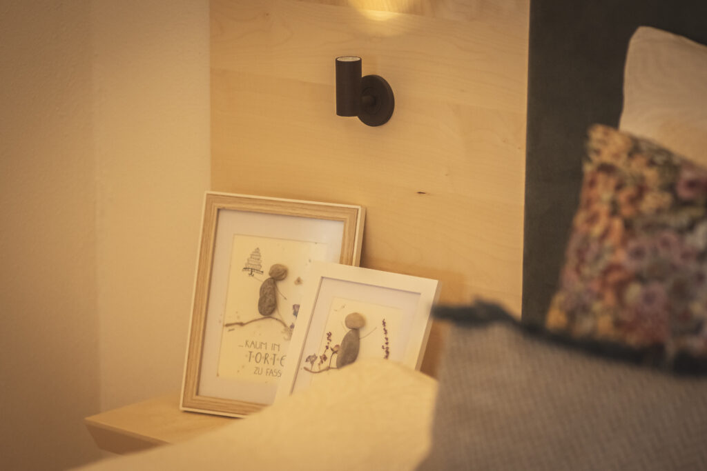 Ablage neben dem Bett in der Suite Herberstein, zwei gerahmte Bilder unter einer Wandleuchte