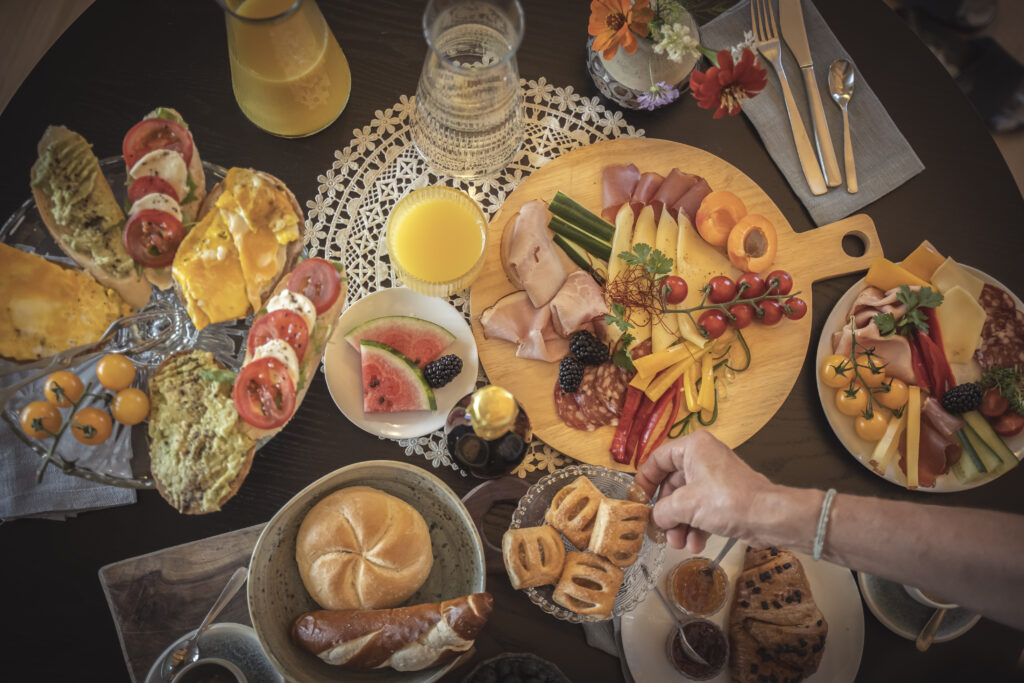 Gedeckter Frühstückstisch mit hausgemachtem Gebäck und Produkten aus dem eigenen Garten